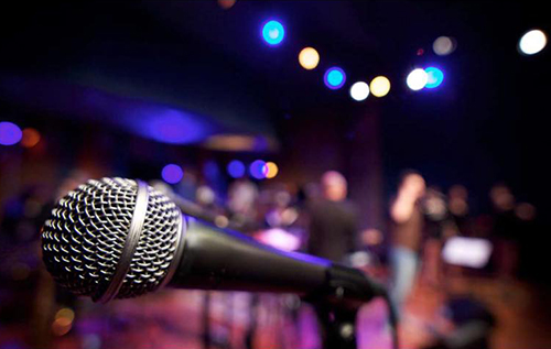 A microphone in the foreground with lights and a ground out of focus in the background